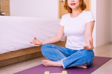 Fototapeta na wymiar Happy woman sitting practicing doing yoga meditation in bedroom,Healthy and lifestyle concept