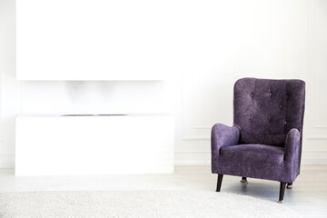 Modern living room interior - purple armchair, fireplace and soft rug against white walls