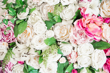 Artificial flowers background of white and pink roses and green leaves