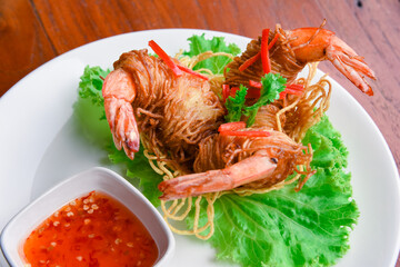 Goong Sarong  noodles Wrapped Shrimp With Crispy Noodle Serve, vegetable and sauce in white plate  on wood table , Thai food