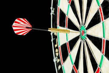Darts on a black background. 1 dart flies directly to the center of the target. Business center goal concept