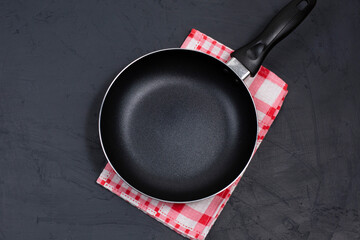 Empty black frying pan or skillet on a red checkered napkin