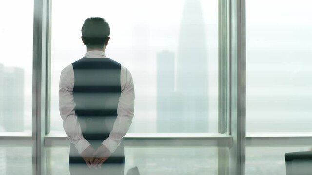 young asian corporate executive welcoming and shaking hands with visiting client in front of windows in office