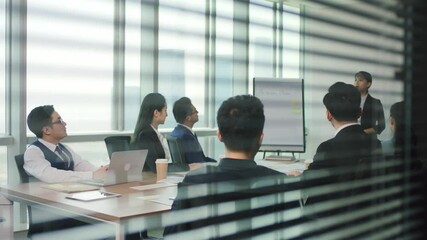 junior asian executive presenting business plan to team during staff meeting in modern office conference room