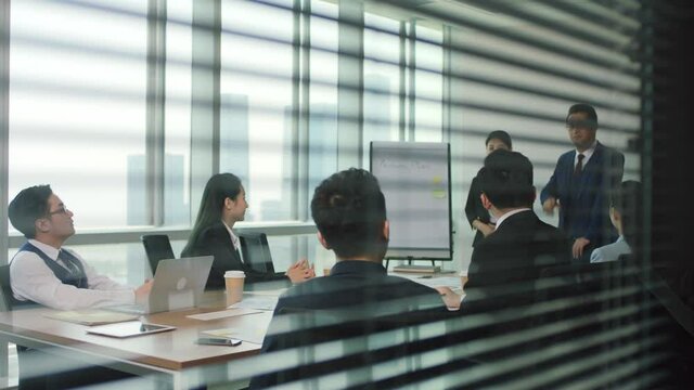 asian manager introducing new team member during staff meeting in modern office conference room