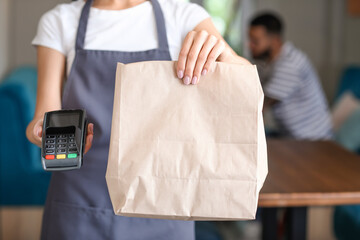 Young waitress with food for delivery and payment terminal in restaurant
