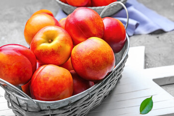 Sweet ripe nectarines in basket on grey background