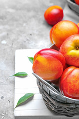 Sweet ripe nectarines in basket on grey background