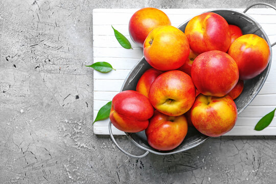 Sweet ripe nectarines in basket on grey background