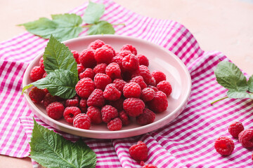 Plate with tasty ripe raspberries on table