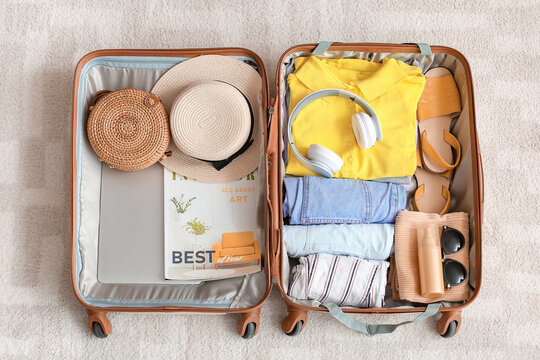 Packed suitcase with belongings on floor. Travel concept