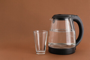 Electric kettle with glass on color background
