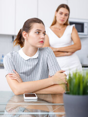 Two upset girls after quarrel at kitchen table