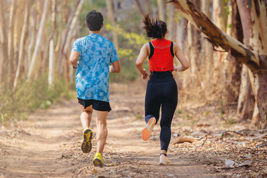 Young couple runner running trail in to a wild dry forest during summer on forest path.