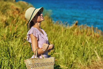 Portrait of a young beautiful woman in a summer dress and a straw hat on a summer walk by the sea