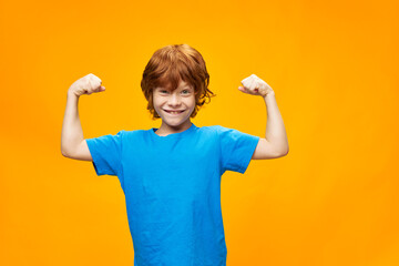 Beautiful red-haired boy shows the muscles of his arms 