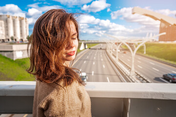 Young woman looking at a road section of St. Petersburg Western high-speed diameter in the sunlight