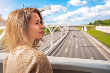 Young woman looking at a road section of St. Petersburg Western high-speed diameter in the sunlight