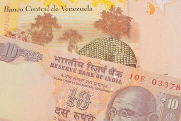 A macro image of a orange ten rupee bill from India paired up with a colorful, yellow five Bolivar bank note from Venezuela.  Shot close up in macro.