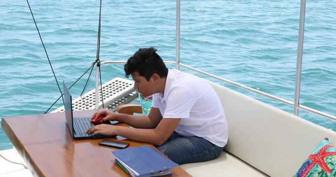 Young boy on yacht deck using laptop computer