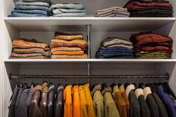 sale, shopping and fashion concept - clothes on shelves and hanger at men's clothing store