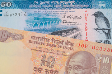 A macro image of a orange ten rupee bill from India paired up with a blue and white fifty rupee bank note from Sri Lanka.  Shot close up in macro.