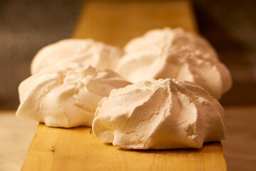 Off white marshmallow roses on wooden surface. Delicious homemade meringue cakes. The concept of home cooking of food.