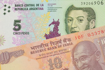 A macro image of a orange ten rupee bill from India paired up with a colorful five peso note from Argentina.  Shot close up in macro.
