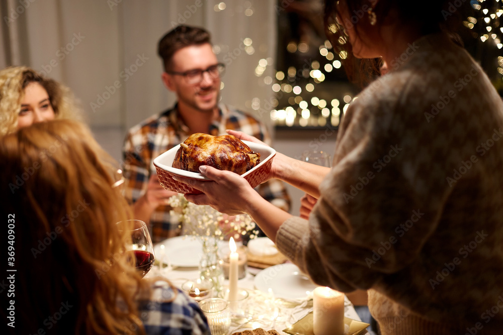 Wall mural holidays, celebration and people concept - happy smiling friends having roast chicken or duck for christmas dinner at home in evening