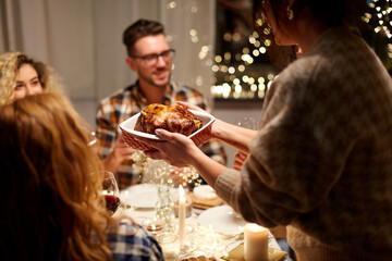 holidays, celebration and people concept - happy smiling friends having roast chicken or duck for christmas dinner at home in evening © Syda Productions