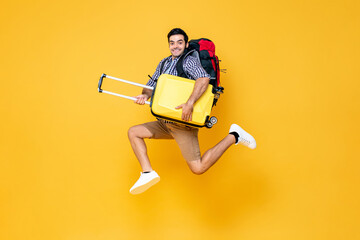 Young excited Caucasian male tourist with baggage jumping in mid-air ready to travel isolated on...