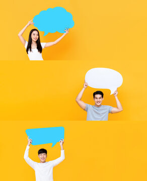 Group of happy smiling Asian men and woman holding speech bubbles with empty spaces for text on isolated yellow studio background
