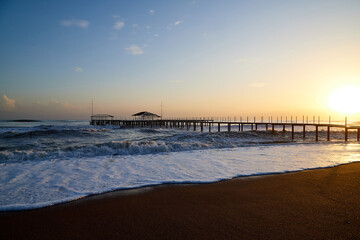 Water of sea, waves with white foam, pierce and sky with sunset in a nice evening.