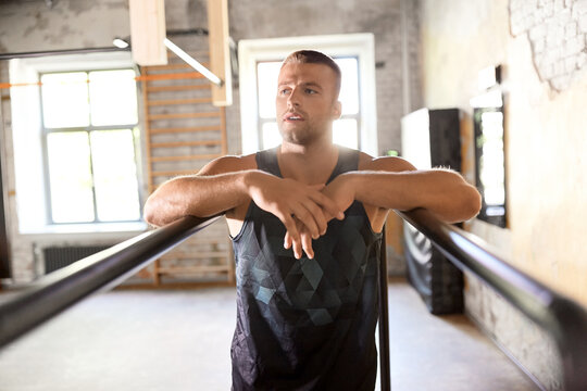 fitness, sport, training and lifestyle concept - young man exercising on parallel bars in gym