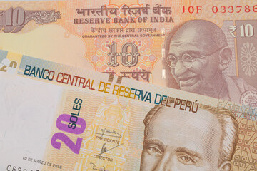 A macro image of a orange ten rupee bill from India paired up with a beige, twenty sol bill from Peru.  Shot close up in macro.