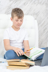 Smart boy doing homework on a bed at home
