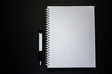 Notepad and pen on black background