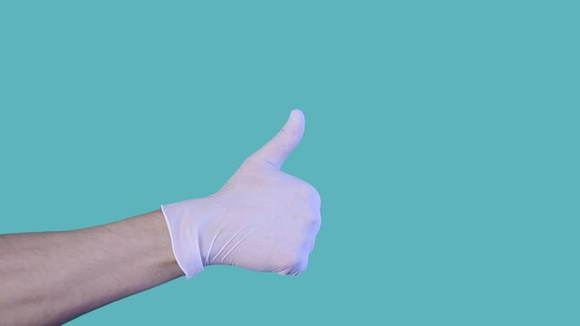 Person in medical gloves continually showing hand gesture thumb up. Dont worry after covid-19 or post-pandemic period. Celebrating victory over coronavirus.Isolated on blue background.Health concept.