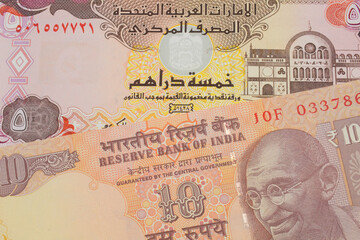A macro image of a orange ten rupee bill from India paired up with a colorful five dinar bank note from the United Arab Emirates.  Shot close up in macro.