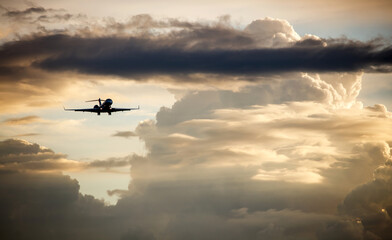 Silhouette of business jet landing on the background of sunset