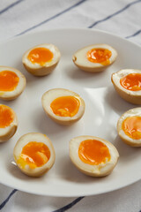Homemade Unami Soy Sauce Eggs on a white plate, low angle view.