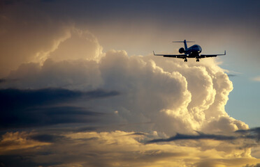 Silhouette of business jet landing on the background of sunset