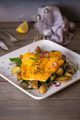 Cod fish fillets with potatoes, mushrooms and spinach on white plate. vertical photo
