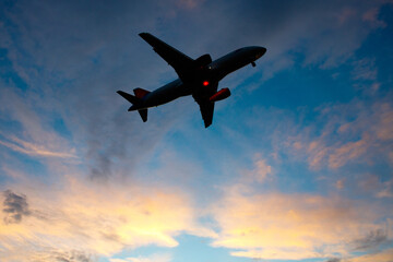 A passenger plane comes in for landing against the background of the evening sky