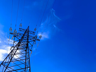 High voltage post or power transmission tower agains blue sky. Silhouette of electricity post and...