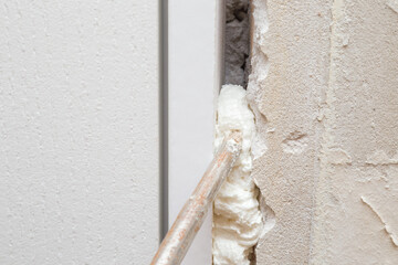 Spray gun filling gap with construction foam between new door and wall. Closeup. Repair work of home. Renovation process. - obrazy, fototapety, plakaty