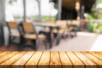 Empty wooden desk space and blurry background of coffee shop or Restaurant for product display montage.