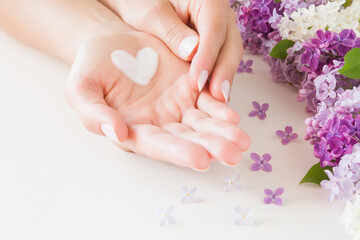 Young, perfect, clean woman hands on white table. Natural herbal skin cream. Heart shape created...