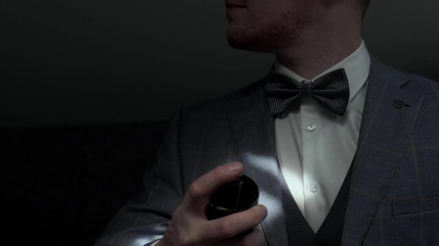 businessman uses perfume. A man in a suit with a bow tie uses perfume