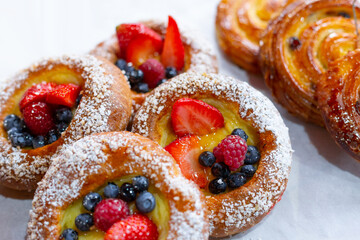 Round delicious buns with blueberries, raspberries and strawberries sprinkled with powdered sugar.. The homemade cakes and pastries are handmade. Private bakery, pastry shop